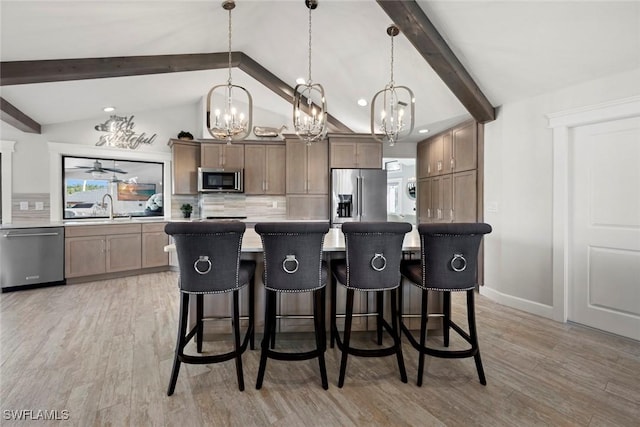 kitchen with a breakfast bar, pendant lighting, stainless steel appliances, and a kitchen island