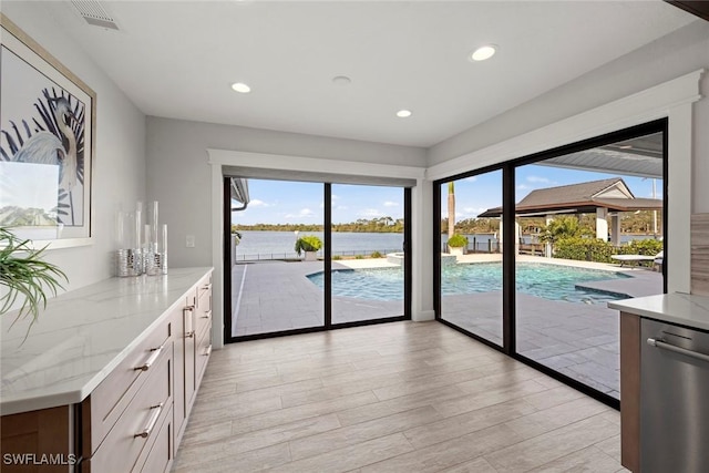 interior space featuring a healthy amount of sunlight, a water view, and light hardwood / wood-style flooring