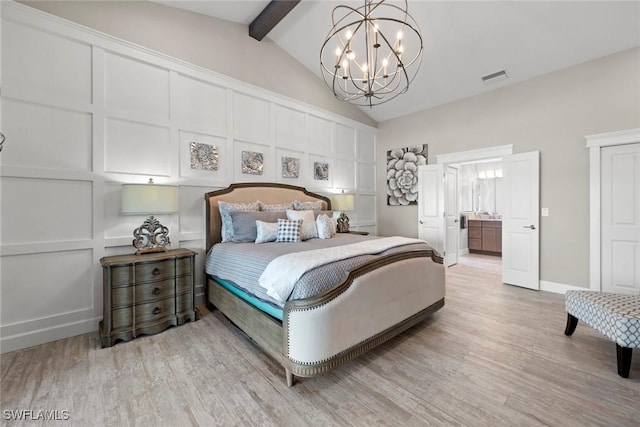 bedroom featuring ensuite bathroom, lofted ceiling with beams, light wood-type flooring, and a chandelier