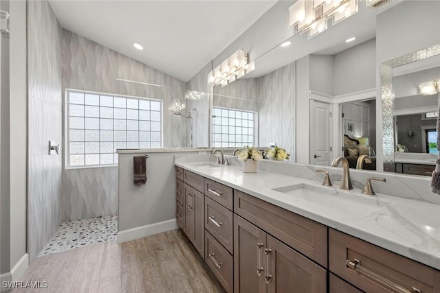 bathroom with hardwood / wood-style floors, vanity, and a tile shower