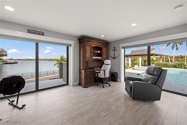 office area featuring a water view, light hardwood / wood-style flooring, and plenty of natural light