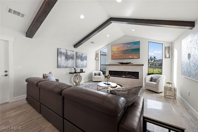 living room featuring lofted ceiling with beams, a high end fireplace, and light hardwood / wood-style flooring