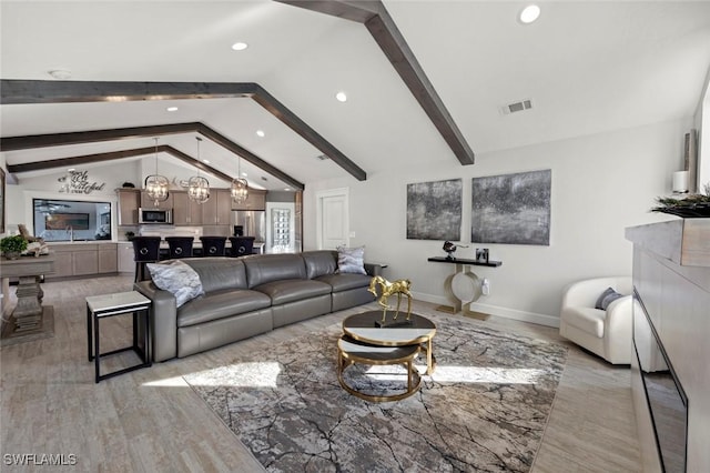 living room featuring vaulted ceiling with beams, light hardwood / wood-style floors, a notable chandelier, and sink