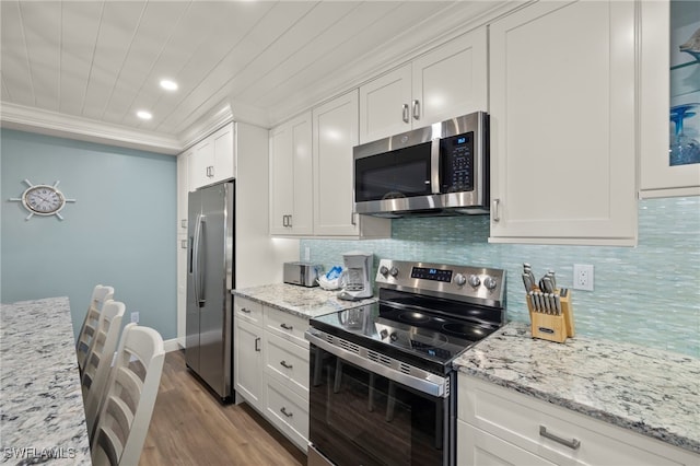 kitchen featuring light stone countertops, light wood-type flooring, tasteful backsplash, stainless steel appliances, and white cabinets