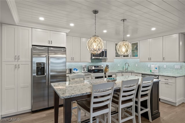 kitchen with white cabinets, an island with sink, light wood-type flooring, and appliances with stainless steel finishes