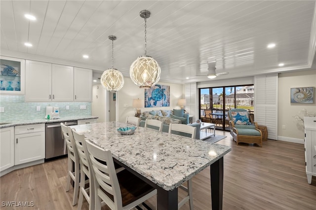 kitchen featuring decorative backsplash, a kitchen breakfast bar, ceiling fan, dishwasher, and white cabinetry