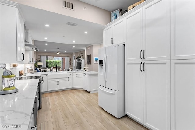 kitchen with sink, white cabinetry, light stone counters, white fridge with ice dispenser, and light hardwood / wood-style floors