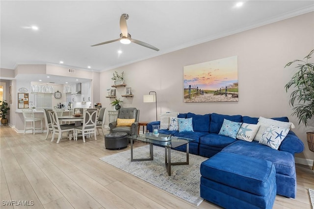 living room featuring ceiling fan, crown molding, and light hardwood / wood-style floors