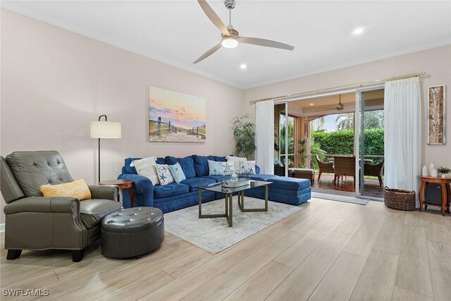 living room with crown molding, ceiling fan, and light wood-type flooring