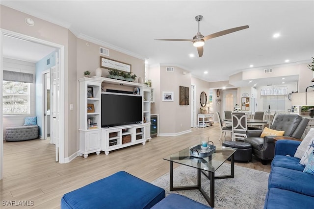 living room featuring light hardwood / wood-style floors, ceiling fan, and crown molding