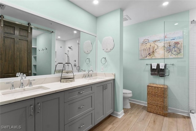 bathroom featuring vanity, wood-type flooring, a shower with door, and toilet