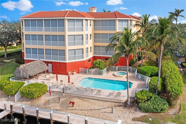 view of swimming pool with a boat dock, a patio area, and a hot tub