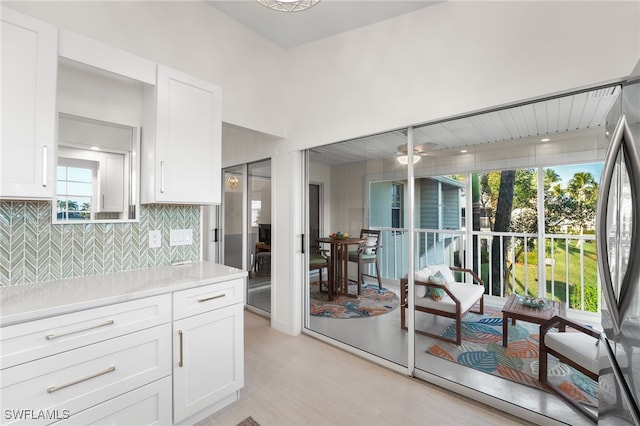 kitchen with tasteful backsplash, stainless steel refrigerator, and white cabinetry