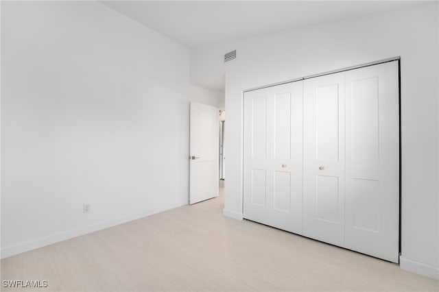 unfurnished bedroom with light hardwood / wood-style flooring and a closet