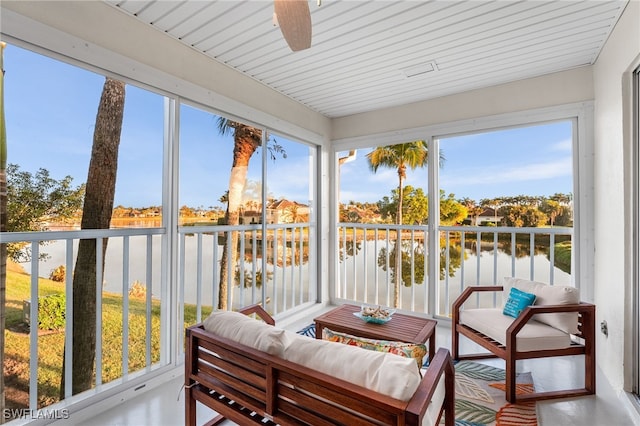 sunroom featuring ceiling fan and a water view