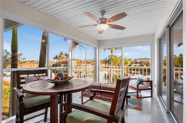 sunroom with a water view and ceiling fan