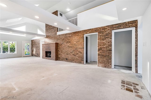 unfurnished living room with lofted ceiling, a fireplace, and brick wall