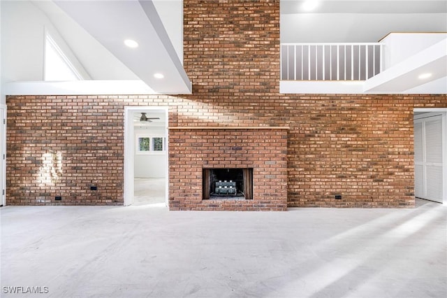 unfurnished living room with a fireplace, ceiling fan, lofted ceiling, and brick wall