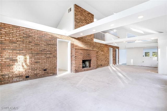 unfurnished living room with high vaulted ceiling, a fireplace, and brick wall