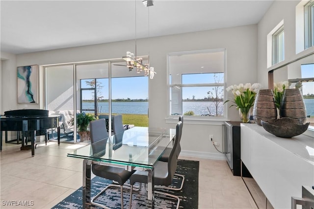 dining room with a water view, a notable chandelier, and light tile patterned floors