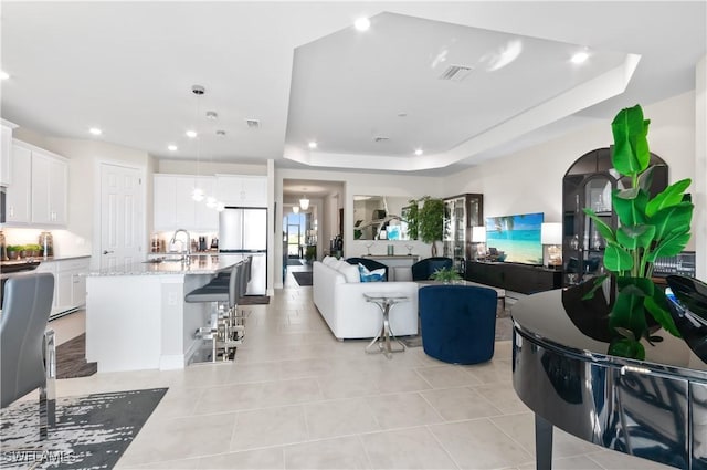 tiled living room with a raised ceiling and sink