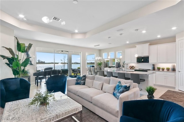 living room featuring a water view and a raised ceiling