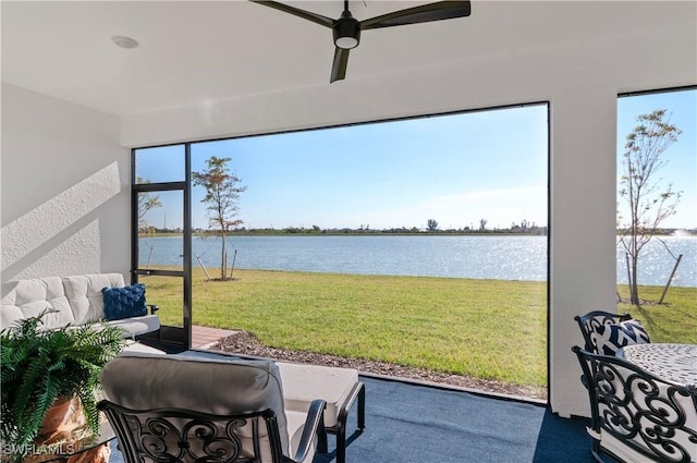 sunroom / solarium featuring ceiling fan and a water view