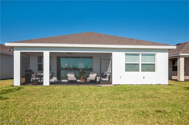 back of house featuring a lawn, a shingled roof, and a sunroom