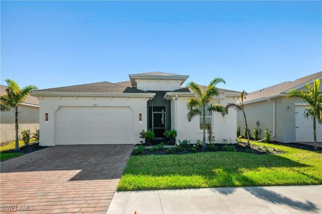 view of front of house with a garage, decorative driveway, a front yard, and stucco siding