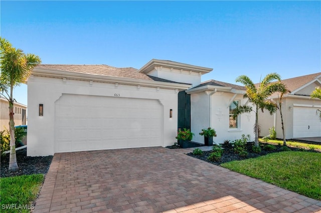 view of front facade featuring stucco siding, an attached garage, and decorative driveway