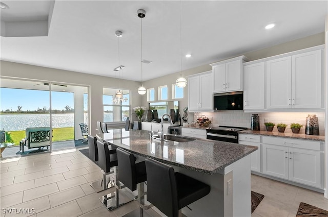 kitchen with white cabinetry, a kitchen island with sink, black electric range, and hanging light fixtures