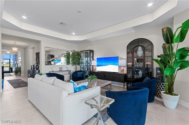 living room with a tray ceiling and light tile patterned flooring