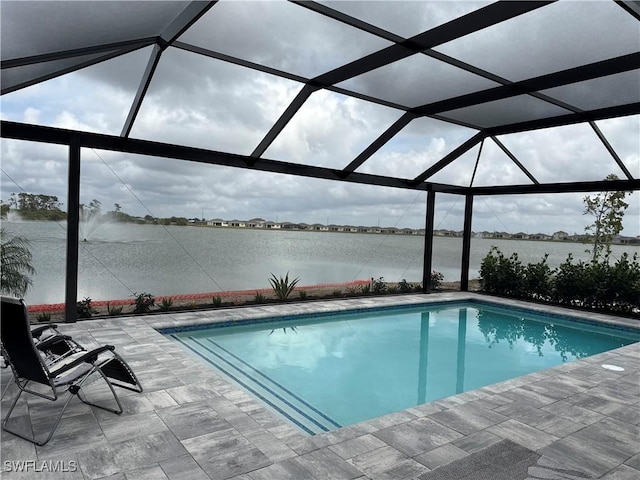 pool with a patio area, glass enclosure, and a water view