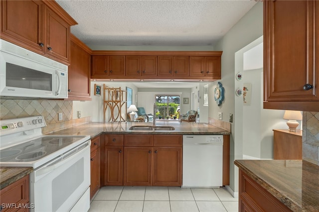 kitchen with white appliances, sink, decorative backsplash, light tile patterned floors, and a textured ceiling