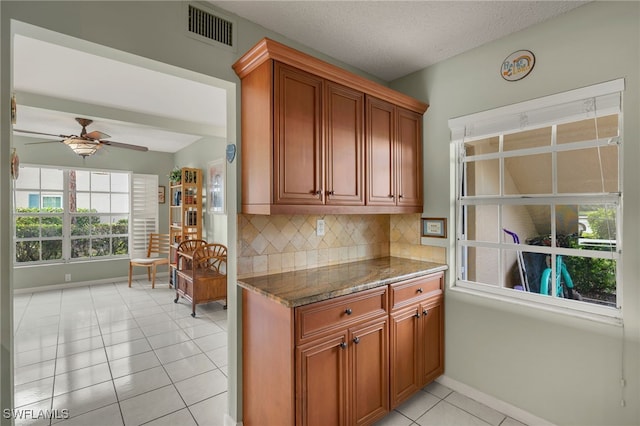 kitchen with dark stone counters, decorative backsplash, ceiling fan, light tile patterned floors, and a textured ceiling