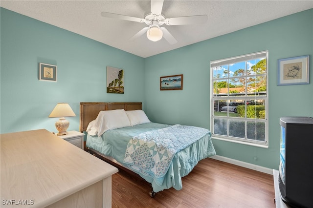 bedroom with wood-type flooring, a textured ceiling, and ceiling fan