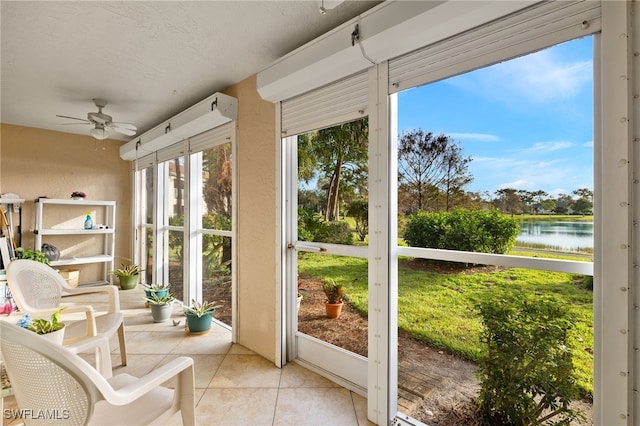 sunroom with ceiling fan and a water view