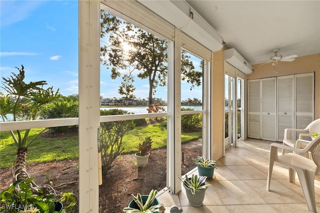 sunroom featuring ceiling fan and a water view