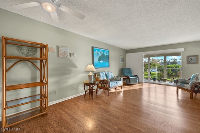 sitting room with ceiling fan, wood-type flooring, and a textured ceiling