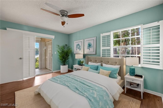 bedroom featuring hardwood / wood-style floors, ceiling fan, a textured ceiling, and multiple windows