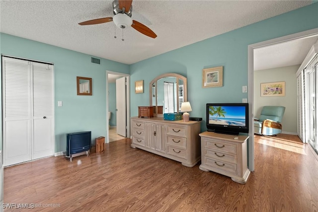 bedroom featuring ceiling fan, light wood-type flooring, and a textured ceiling