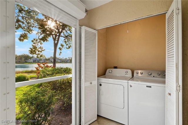 laundry area featuring a water view, separate washer and dryer, and light tile patterned floors