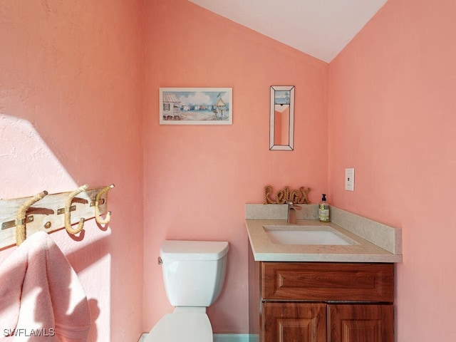 bathroom with vanity, toilet, and lofted ceiling