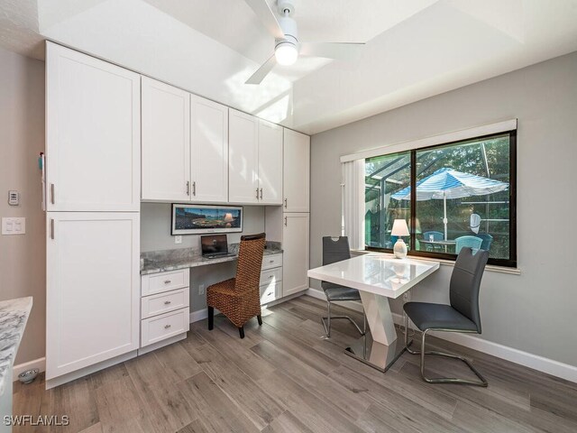 home office with ceiling fan, built in desk, and light wood-type flooring