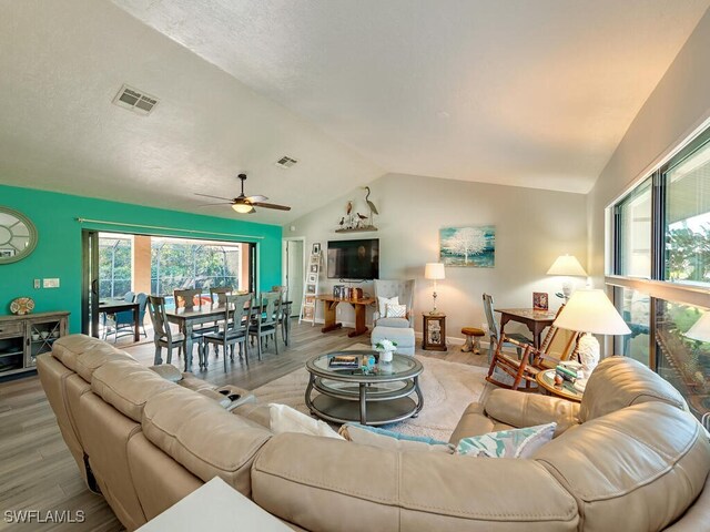 living room featuring vaulted ceiling, light hardwood / wood-style flooring, and ceiling fan