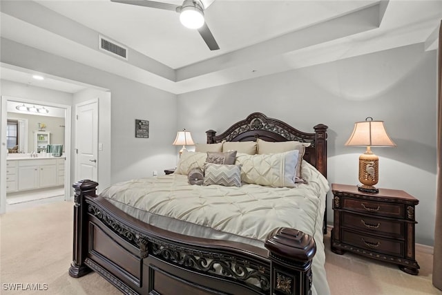 bedroom with ceiling fan, light carpet, and connected bathroom