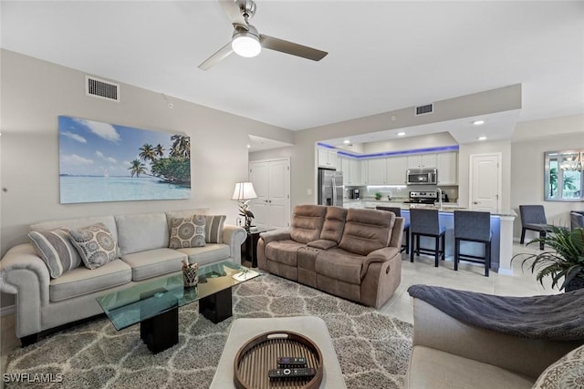 tiled living room featuring ceiling fan and sink