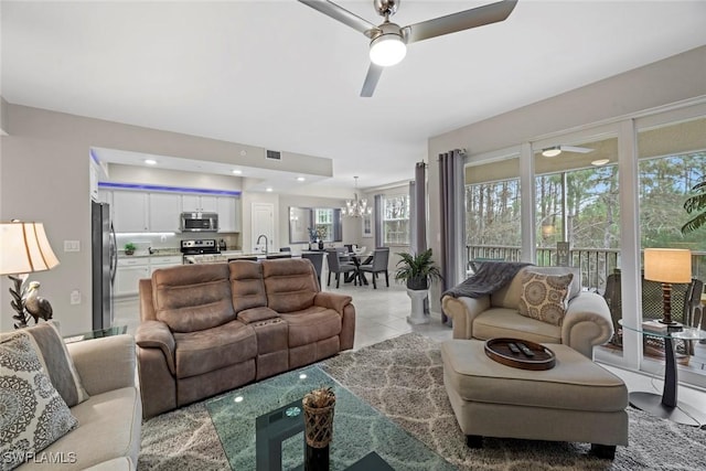 tiled living room featuring plenty of natural light and ceiling fan with notable chandelier