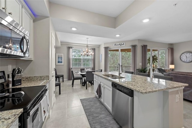 kitchen with white cabinetry, sink, light stone countertops, an island with sink, and appliances with stainless steel finishes