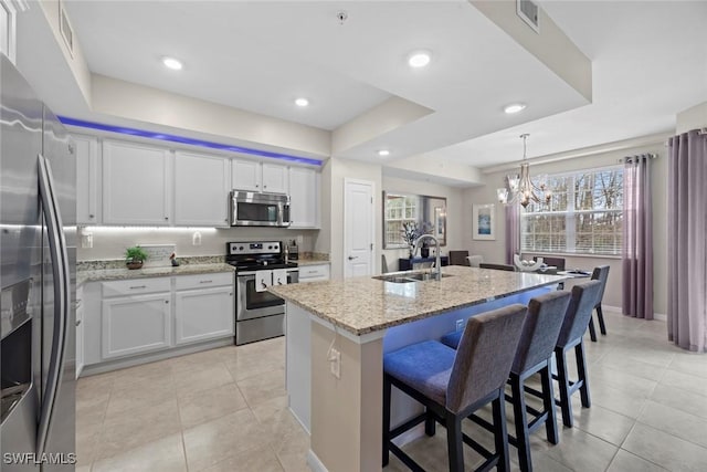 kitchen with sink, white cabinetry, stainless steel appliances, and an island with sink